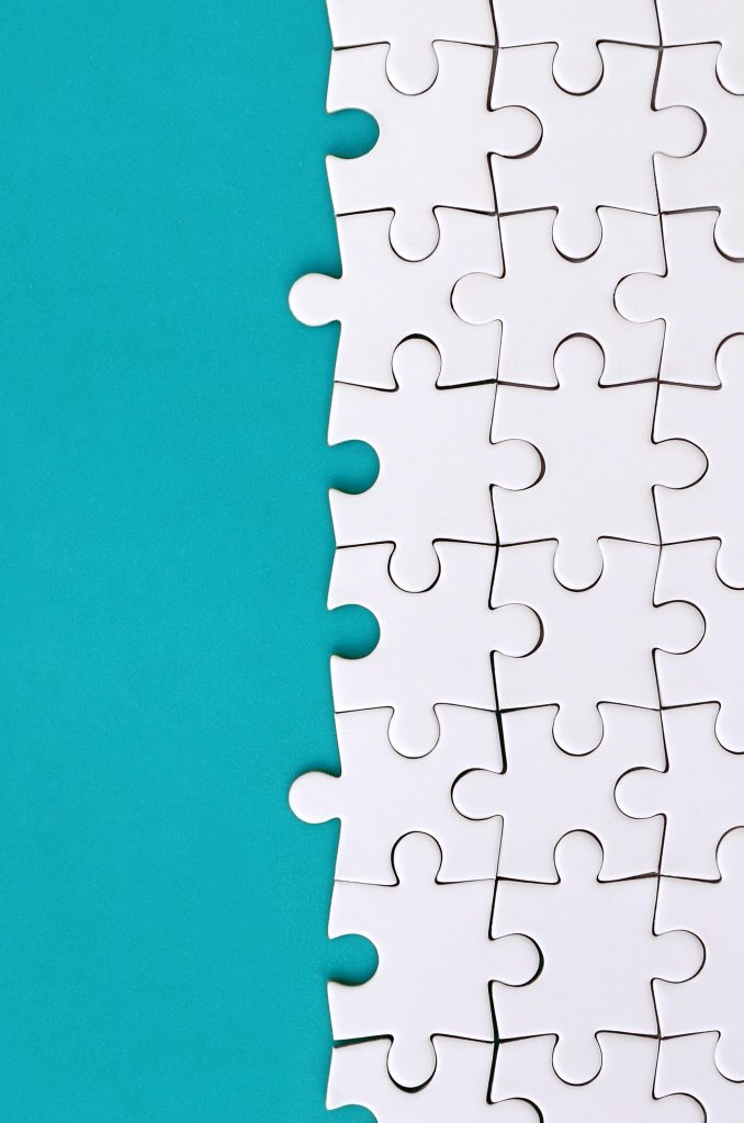 fragment of a folded white jigsaw puzzle on the background of a blue plastic surface. texture photo with copy space for text